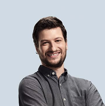 A man with short dark hair and a beard smiles with arms crossed, wearing a gray button-up shirt, against a light gray background—ready to help you book a live custom demo request. C3 Solutions